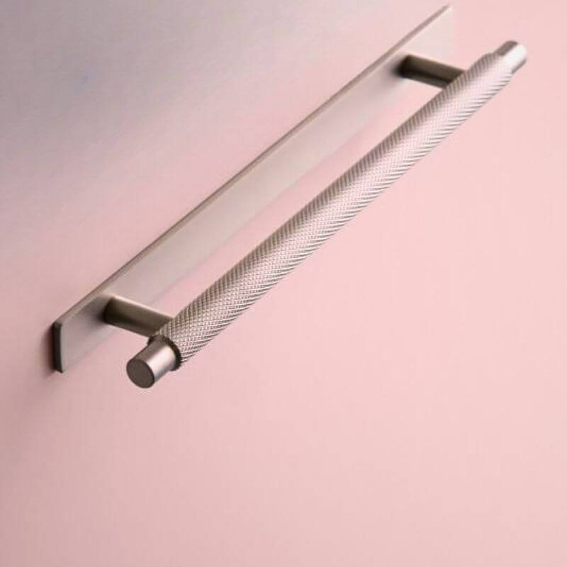 Stainless steel finish handle with back plate on a plain dusky pink background