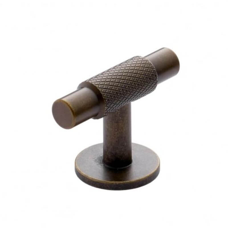 cabinet T-Bar handle in Antique Brass finish on plain grey background