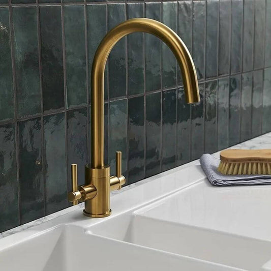 Brass tap on white sink and dark tile background