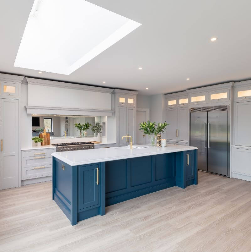 wide kitchen view of navy and off white cabinetry with Buster and Punch Brass Cross Handles